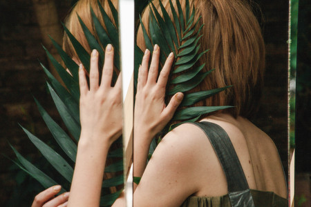 The girl hides in a mirror with a fern branchの写真素材