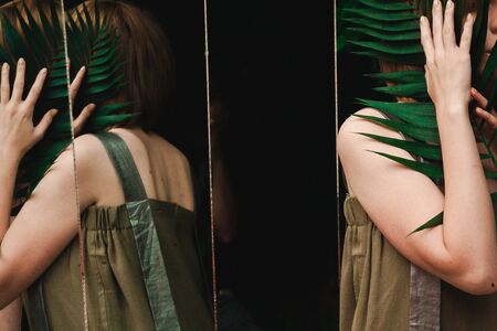 Reflection of a girl with a fern in her hand in a lot of mirrorsの写真素材