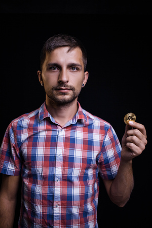 Serious man in a shirt and with a coin bitcoinの写真素材