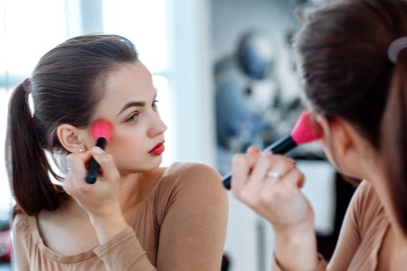 Woman holds cosmetic brush in the faceの写真素材
