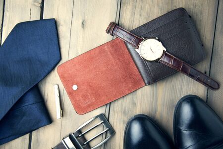 tie, shoes, wallet, watch and belt on wooden tableの写真素材
