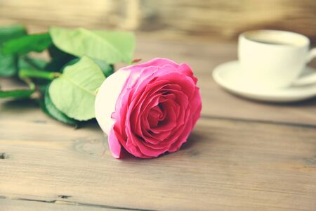 Coffee with pinke rose on wooden tableの写真素材