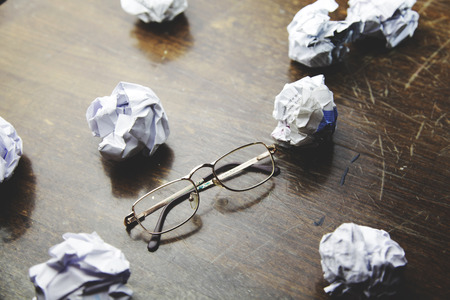 crumpled paper and glasses  on wooden tableの写真素材