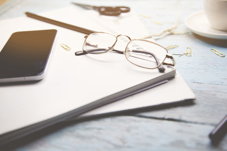 Coffee cup, smartphone,glasses and blank notebook  on wooden tableの写真素材