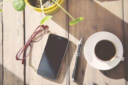 Working table with  coffee cup , pen , smartphone and   glassesの写真素材