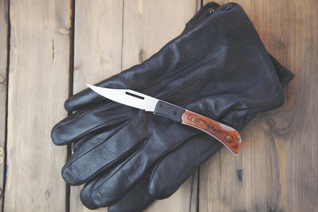 knife on black gloves on wooden tableの写真素材