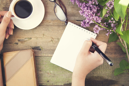 woman hand pen and coffee on wooden tableの写真素材