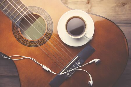 cup of coffee, guitar and earphone on wooden backgroundの写真素材