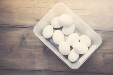 some eggs in white bowl on wooden table