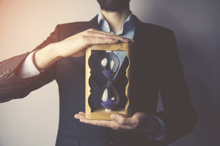 Business man holding hourglass, time conceptの写真素材