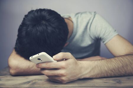working man sleeping on mobile phone at wooden tableの写真素材