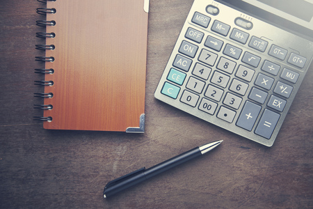 calculator with notebook and pen on a wooden tableの写真素材