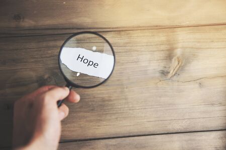 Hand holding magnifying glass with words hopeの写真素材