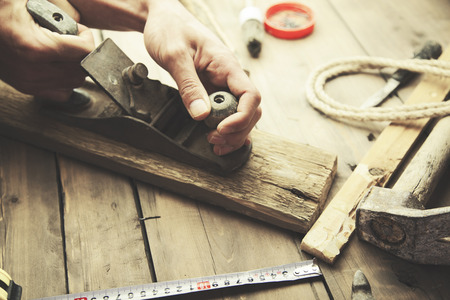 carpenter working with plane on wooden backgroundの写真素材