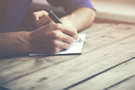 man hand pen and notebook on wooden tableの写真素材