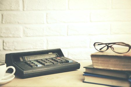glasses on books and calculator,coffee on table on brick wall bacgroundの写真素材
