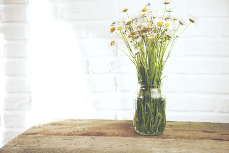 chamomile bouquet in jar on rustic wooden tableの写真素材