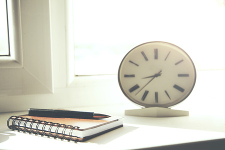clock,notepad  and pen  on window