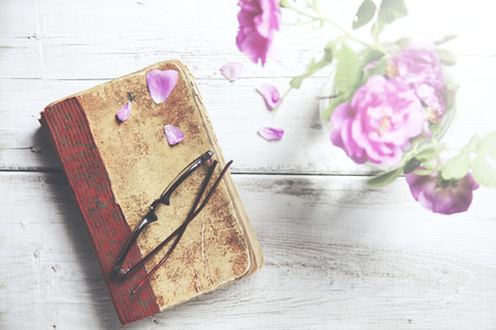 Pink roses in vase,books on wooden tableの写真素材