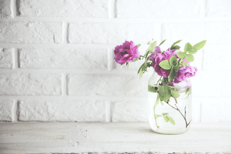 roses in glass vase in brick wall backgroundの写真素材