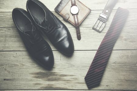 tie, shoes, wallet, watch and belt on wooden tableの写真素材