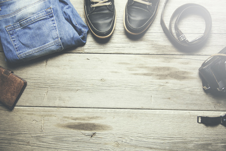 man jeans, belt, wallet, sport shoes and a camera on wooden backgroundの写真素材