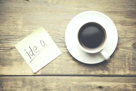 idea on paper and cup of coffee on wooden tableの写真素材