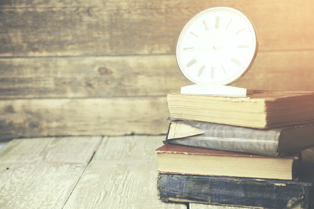 Books and  clock on a wooden background.の写真素材