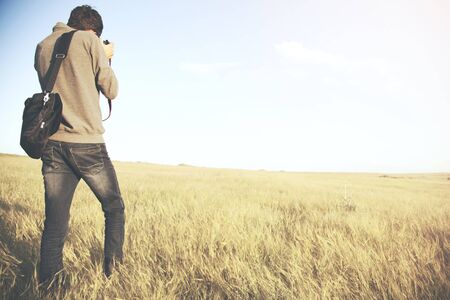 Young man photographer on a fieldの写真素材