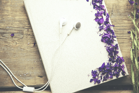 flower petals and headphones on notebook on wooden tableの写真素材