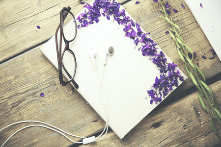 flower petals,headphones and glasses on book on wooden tableの写真素材