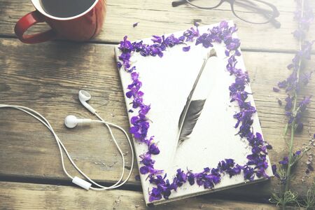 flower petals, headphones, feather, coffee and book on wooden tableの写真素材