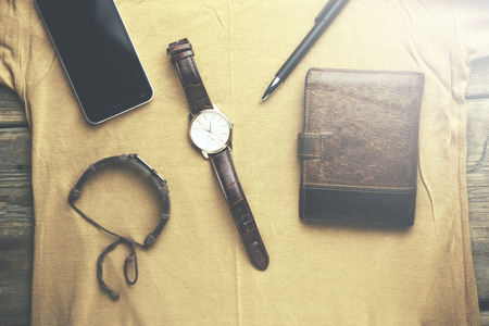 man watches, wallet and phone on yellow shirt
