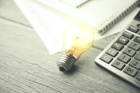 bulb, calculator and notebook on working tableの写真素材
