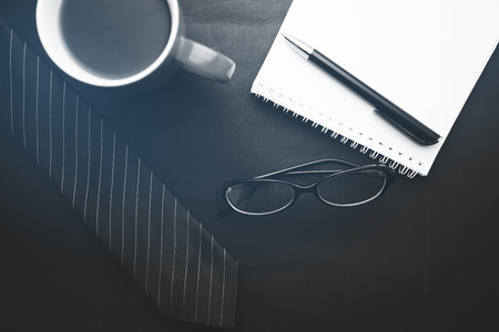 tie,notebook,glasses and coffee on  black backgroundの写真素材