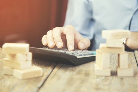 Businessperson hand calculator and  wooden blocks on office deskの写真素材
