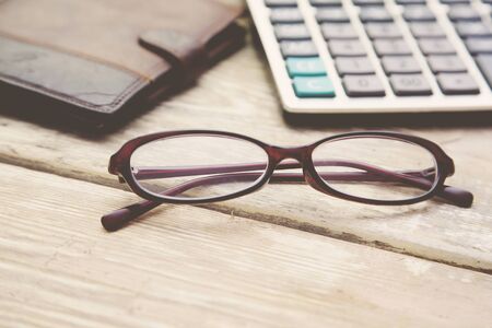 glasses, calculator and wallet on wooden table.の写真素材