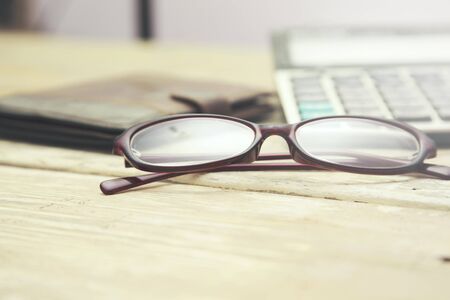 glasses, calculator and wallet on wooden table.の写真素材