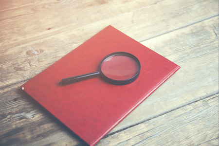 Magnifying lens on folder on wooden tableの写真素材