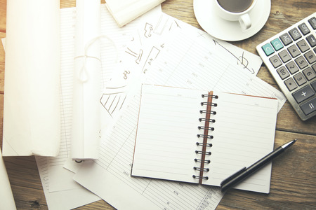 notebook with pen,calculator and cup of coffee on wooden table