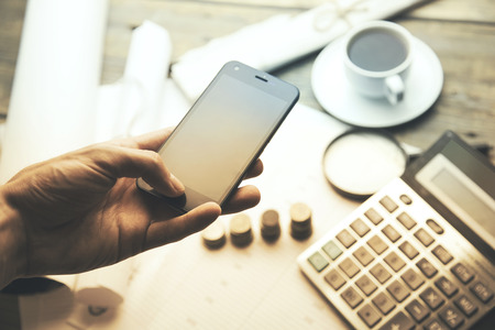 man and phone and ,calculator,money  and cup of coffee on wooden tableの写真素材