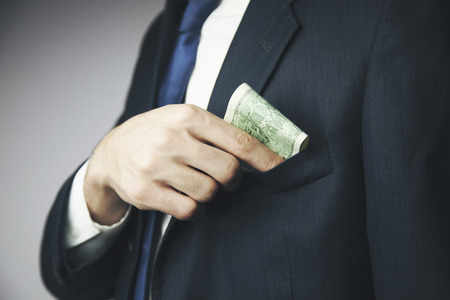 Man hides a bribe into a pocket of his jacketの写真素材