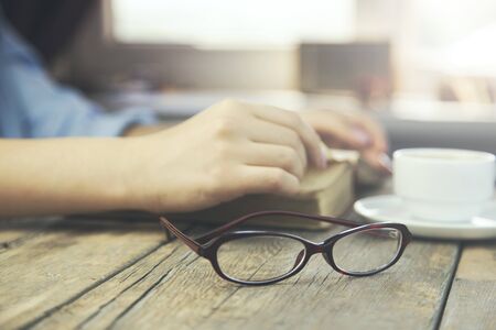 woman sitting by wooden table and reading bookの写真素材