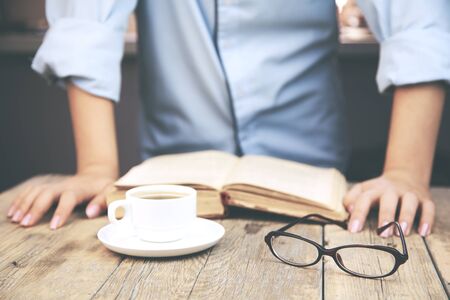 woman reading book and coffee  and glasses on tableの写真素材