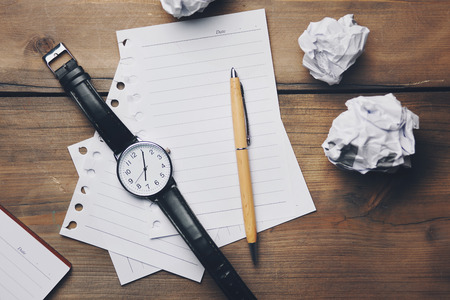 top view of watch and notebook with pen on wooden background