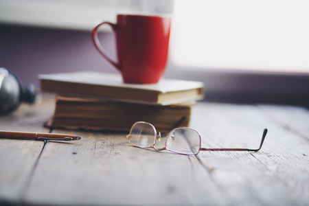 Porcelain cup with coffee on books by the window backgroundの写真素材