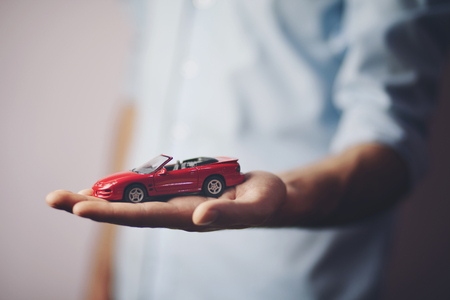 businessman showing a toy car on his palmの写真素材