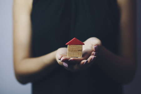A real estate agent holding a small new house in her hands. Conceptualの写真素材