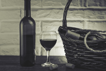 Wine bottles in basket on wooden tableの写真素材