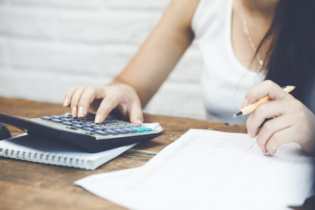 Female hand holding a pen and using calculator while filling in the individual income tax returnの写真素材